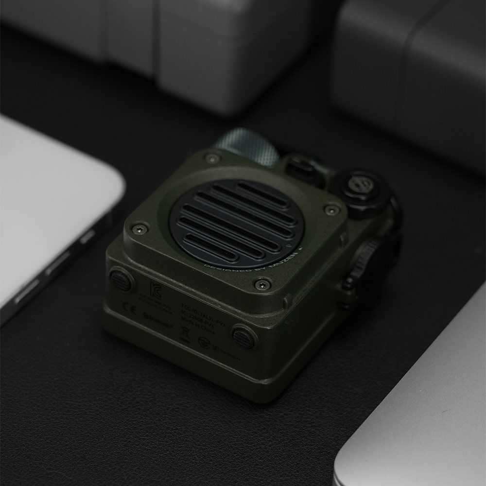 Close-up of a rugged military-style Bluetooth speaker with green metal housing, representing durable tactical gear design